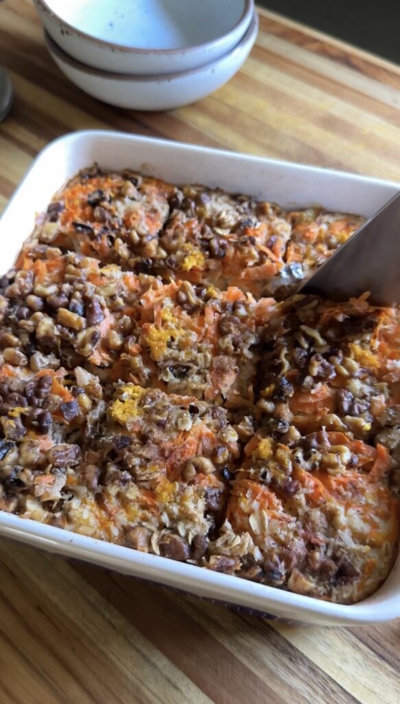 7 layer magic oatmeal bars being cut with a wooden spatula in a baking dish.