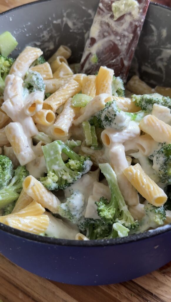 A pot of cottage cheese broccoli pasta is being stirred.