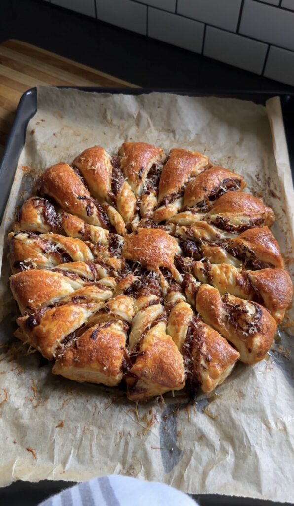 caramelized onion tarte soleil on a parchment-lined baking sheet