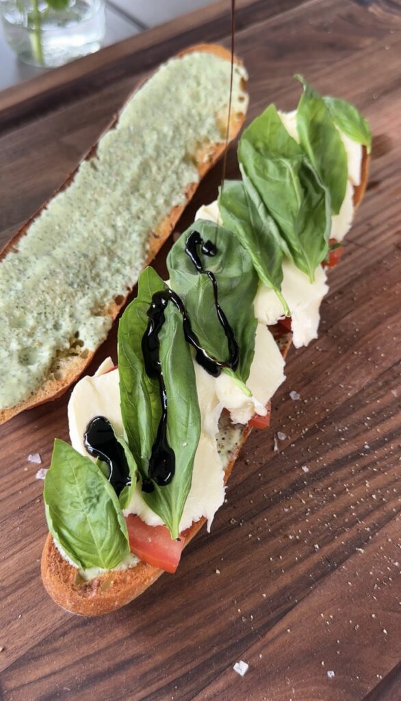 green goddess caprese sandwich sitting on a dark cutting board