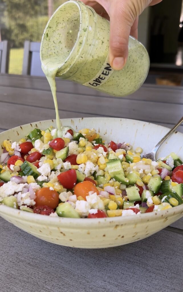 dressing poured over green goddess corn salad