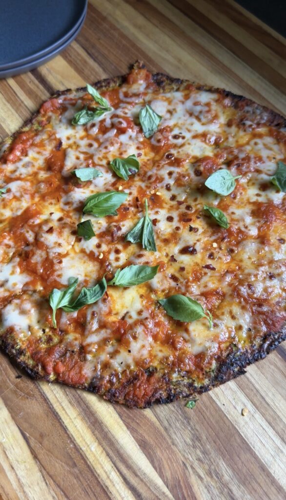 whole zucchini cottage cheese pizza sitting on a wooden cutting board