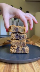 hand placing viral chickpea blondies in a stack on a dark plate