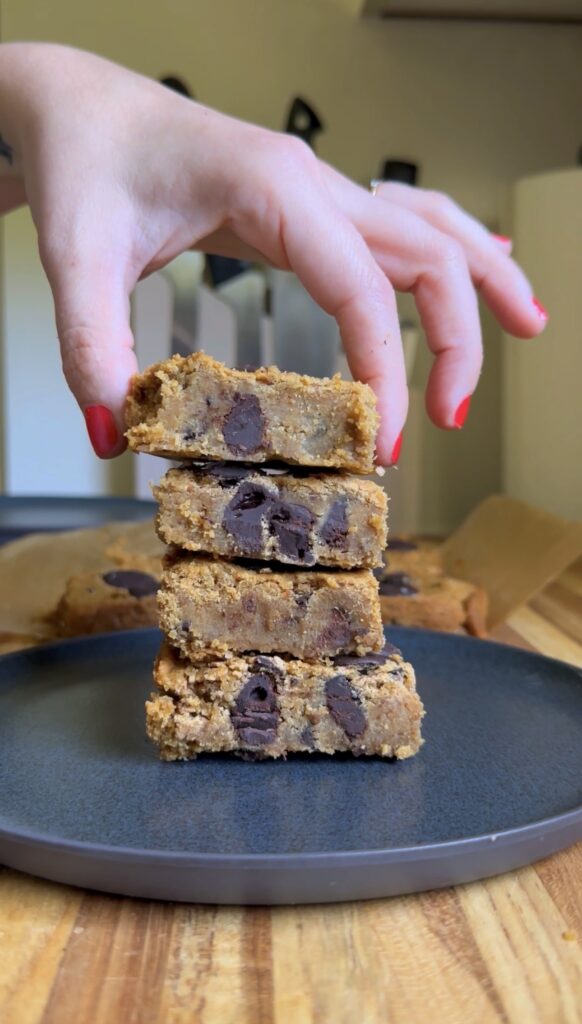 hand placing viral chickpea blondies in a stack on a dark plate