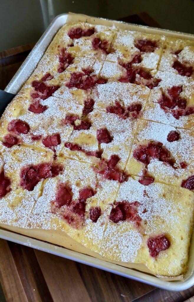 strawberry shortcake sheet pan pancakes on a brown cutting board