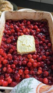 oven mitt holding dish of baked feta cranberry dip