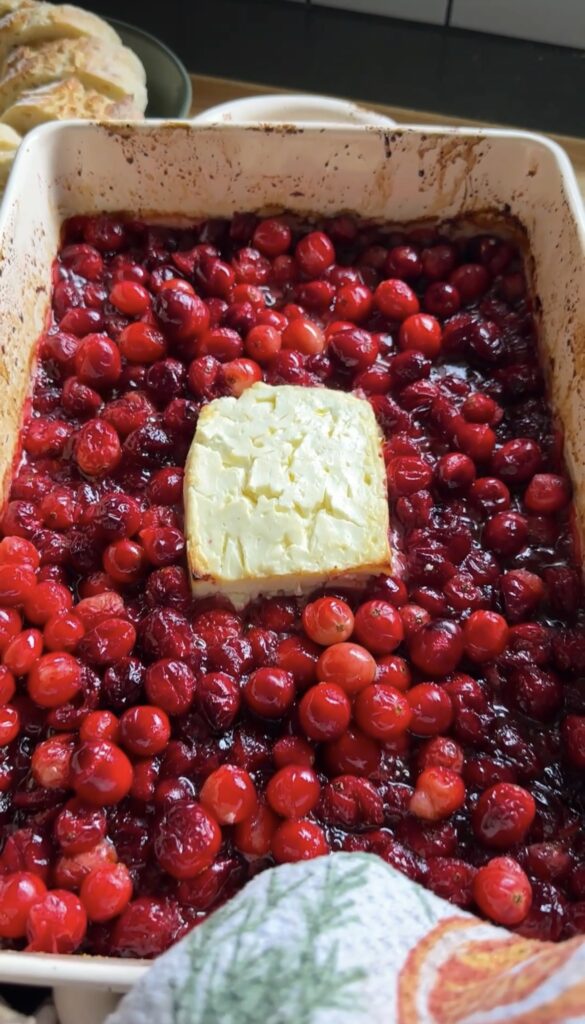 oven mitt holding dish of baked feta cranberry dip