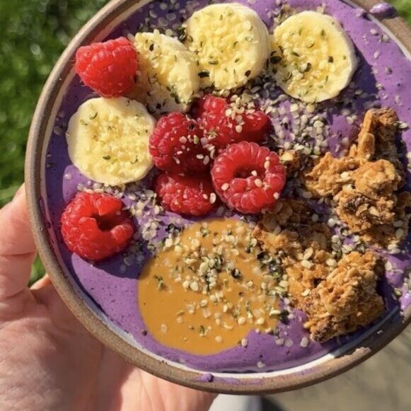 hand holding purple smoothie bowl