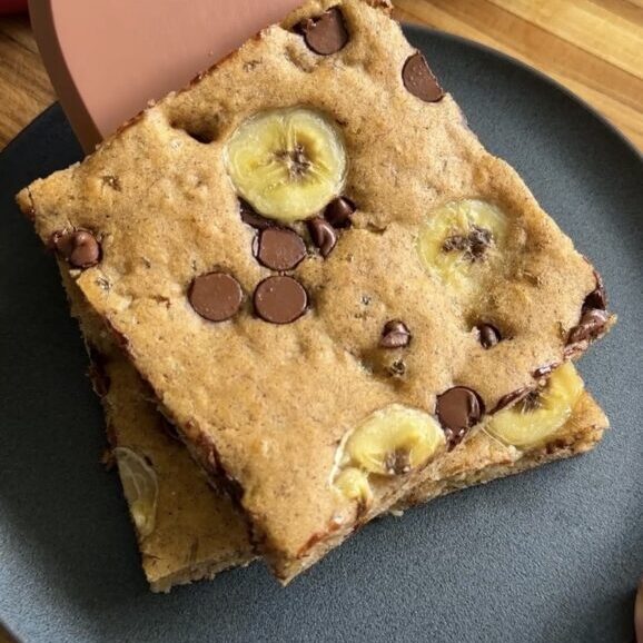 spatula placing banana cottage cheese sheet pan pancakes on black plate