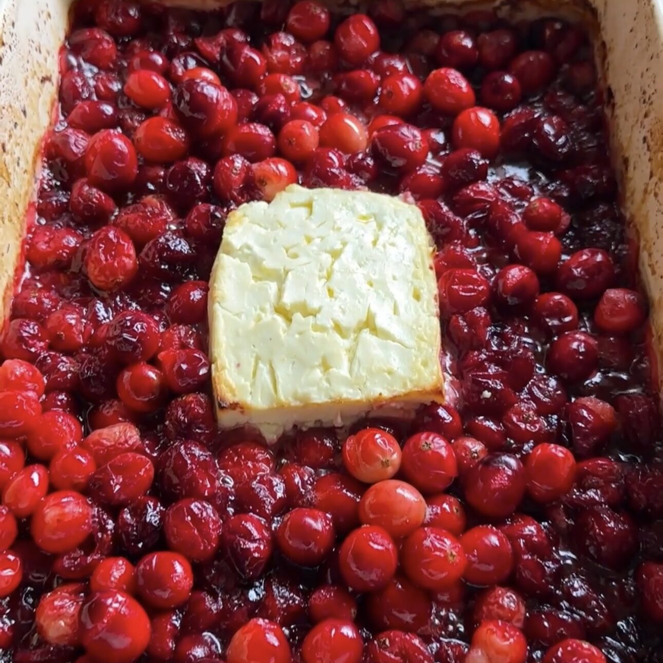 oven mitt holding dish of baked feta cranberry dip