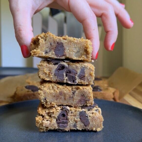 hand placing viral chickpea blondies in a stack on a dark plate