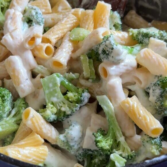A pot of cottage cheese broccoli pasta is being stirred.