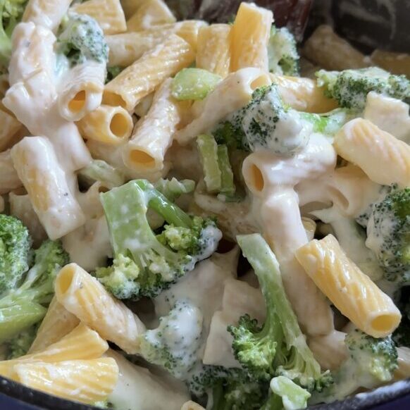 A pot of cottage cheese broccoli pasta is being stirred.