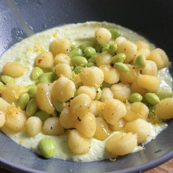 Crispy gnocchi and edamame are plated in a shallow bowl with a green dip.