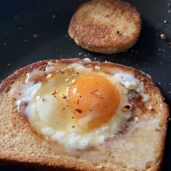 feta fried egg-in-a-hole cooking in a skillet