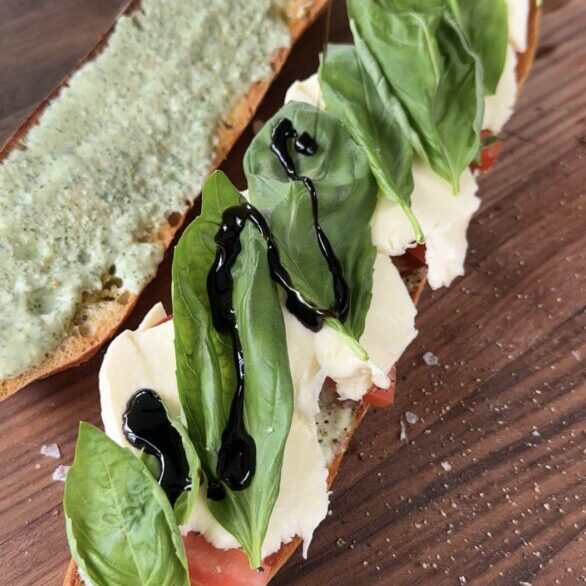 green goddess caprese sandwich sitting on a dark cutting board