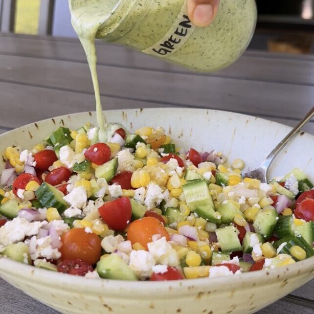 dressing poured over green goddess corn salad