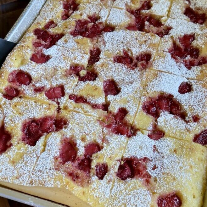 strawberry shortcake sheet pan pancakes on a brown cutting board