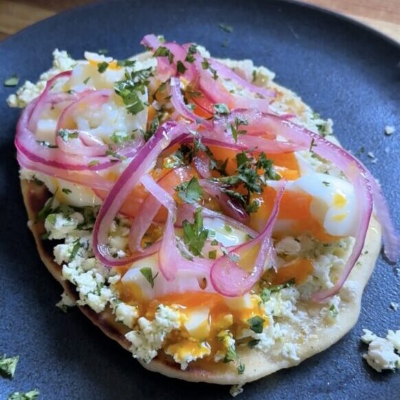 Smashed feta with egg and pickled red onions atop mini naan.