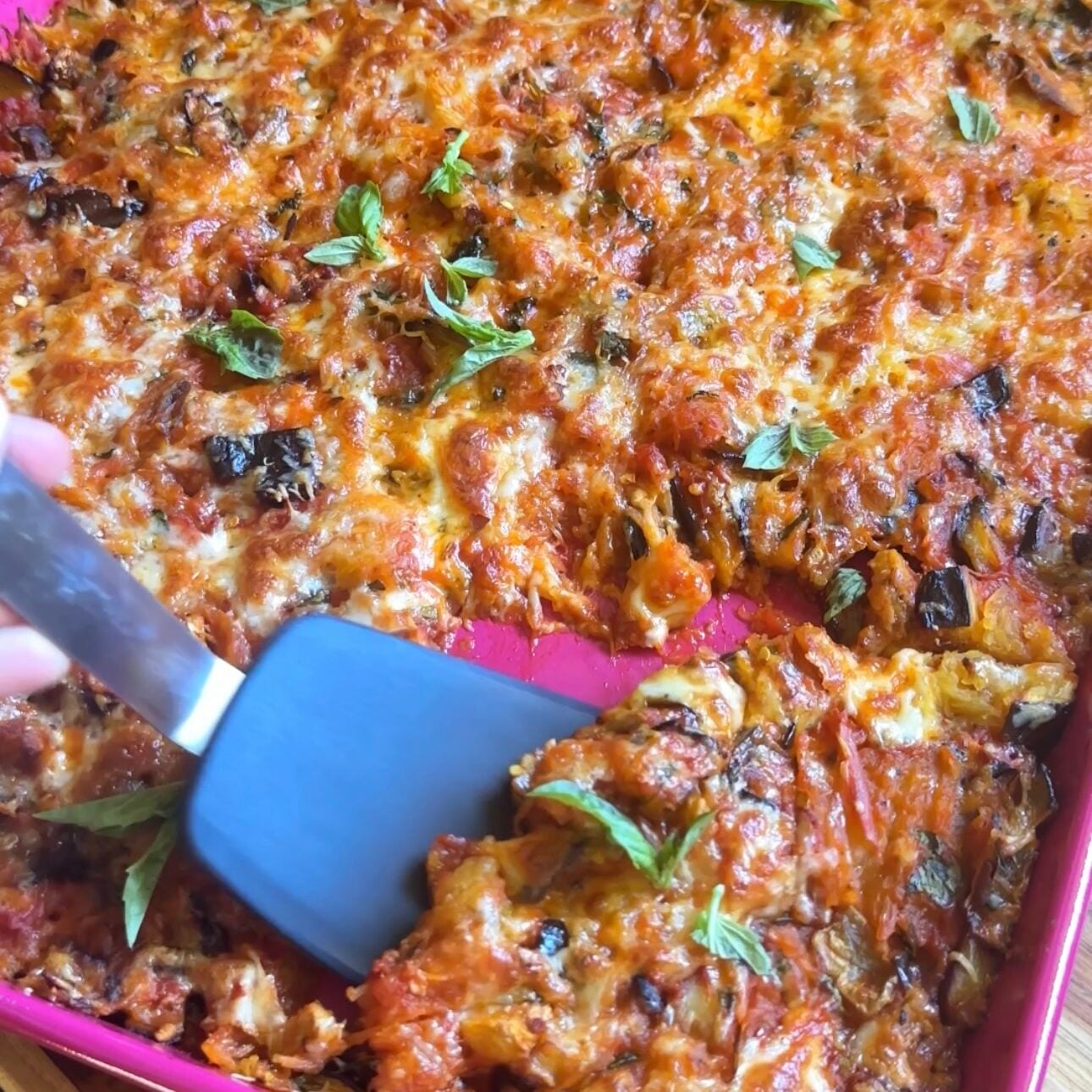 a slice of spaghetti squash alla norma being scooped up with a spatula