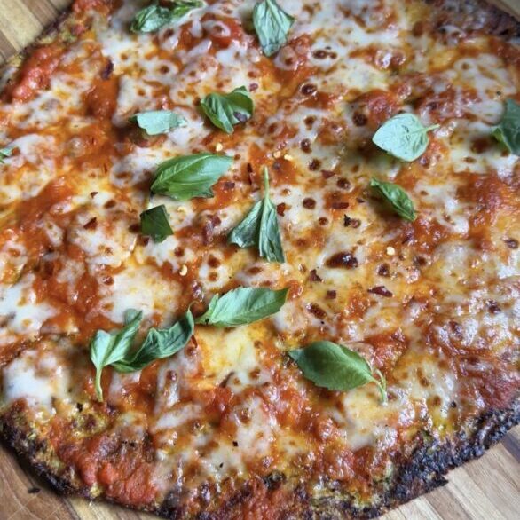 whole zucchini cottage cheese pizza sitting on a wooden cutting board